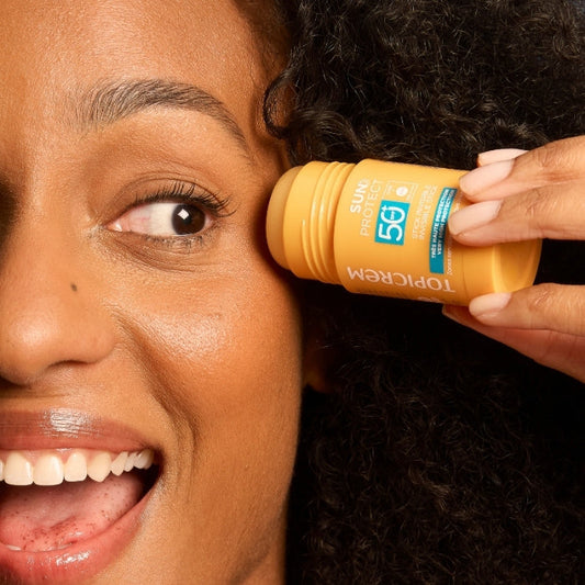 Une jeune femme qui applique le TOPICREM SUN PROTECT Stick Invisible sur son visage