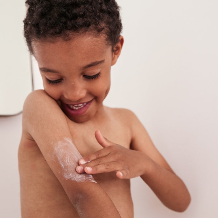 Enfant appliquant une crème hydratante sur le bras pour apaiser une peau atopique