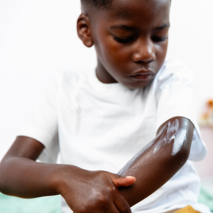 PETIT-GARCON-QUI-S'APPLIQUE-DE-LA-CREME-SUR-LE-BRAS