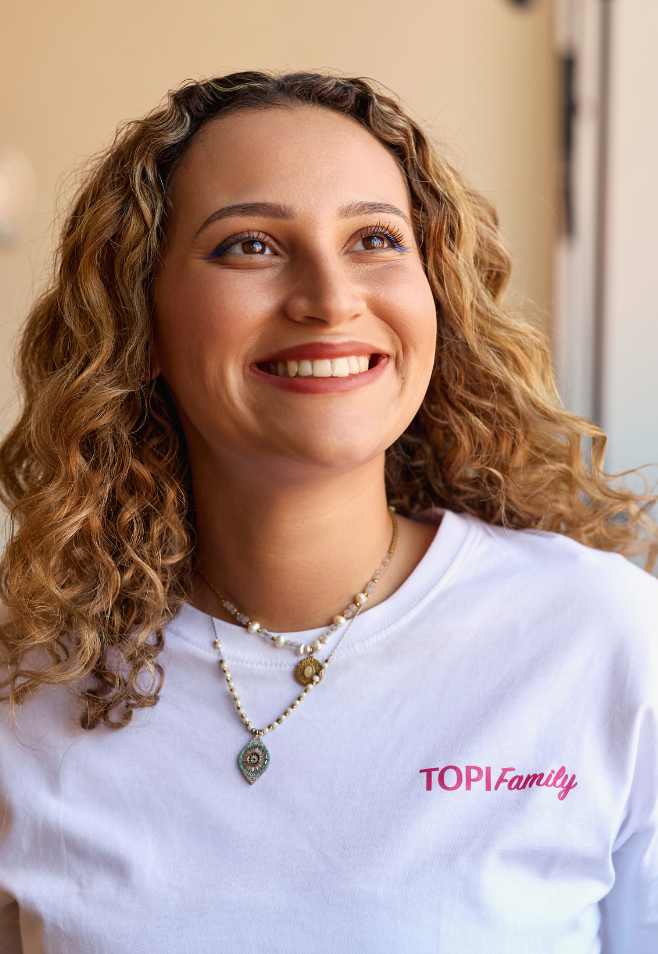 Une femme aux cheveux bouclés qui utilise la gamme KARITE de TOPICREM